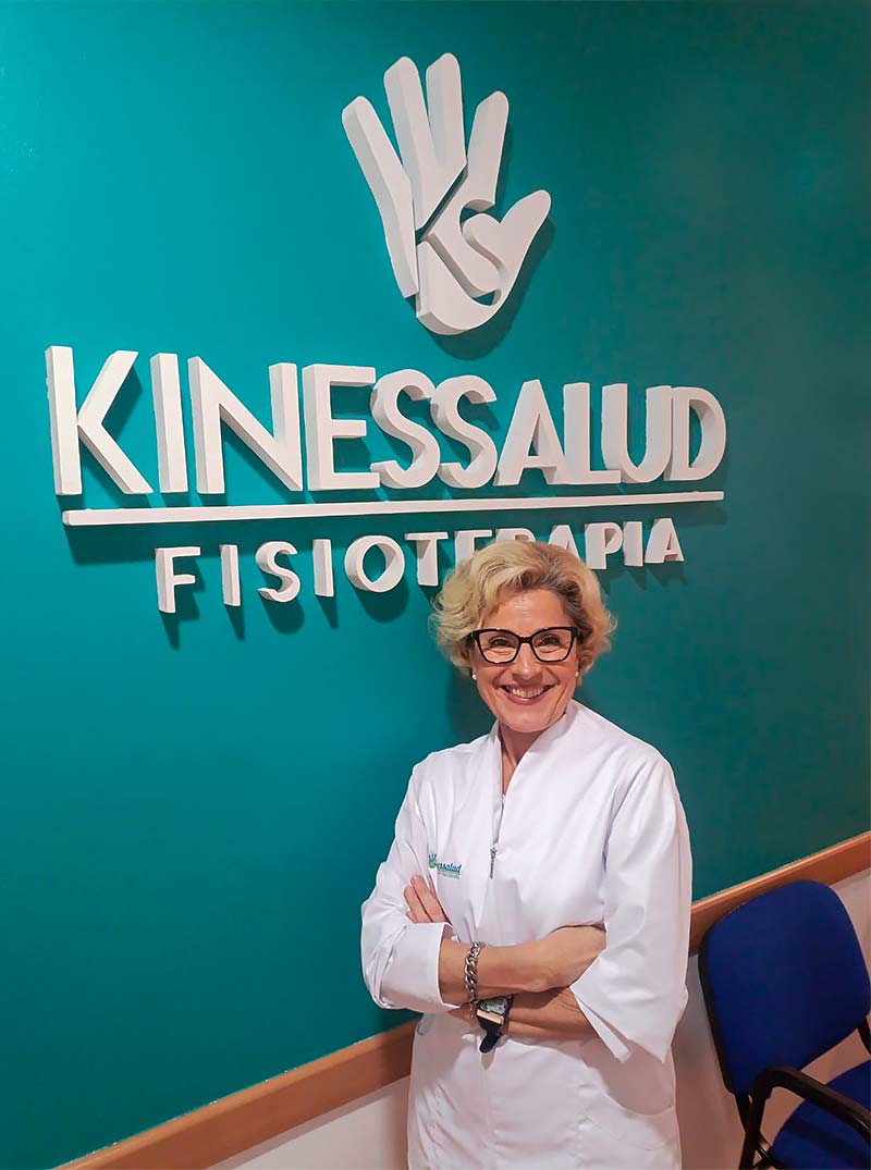 Mujer con gafas frente un cartel que dice Kinessalud Fisioterapia.